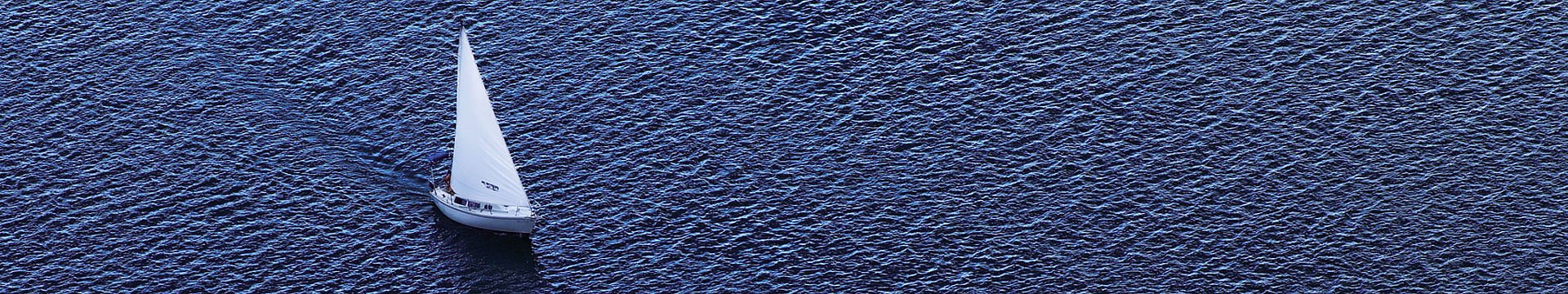 Luftaufnahme eines Segelbootes auf einem dunkelblauen See