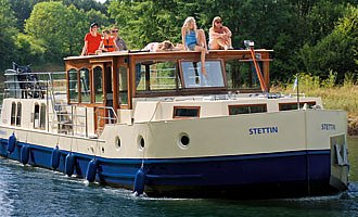 Das Hausboot Kormoran mit einer Gruppe Urlauber an Bord.