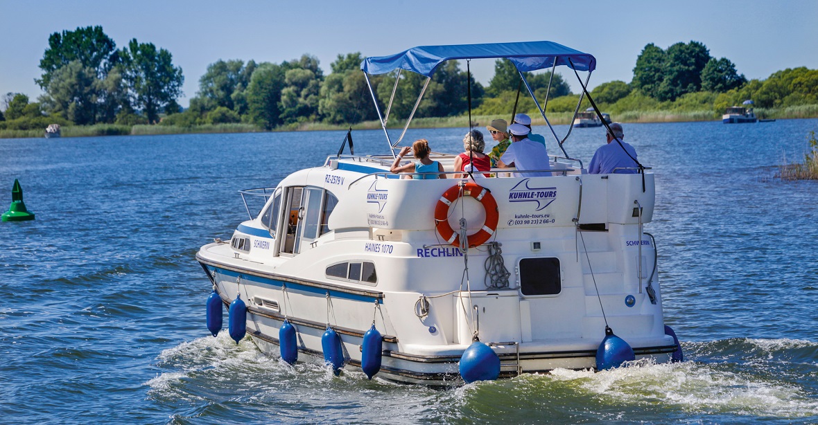 Eine Haines 1070, ein Hausboot der Firma Kuhnle-Tours, fährt über einen See.